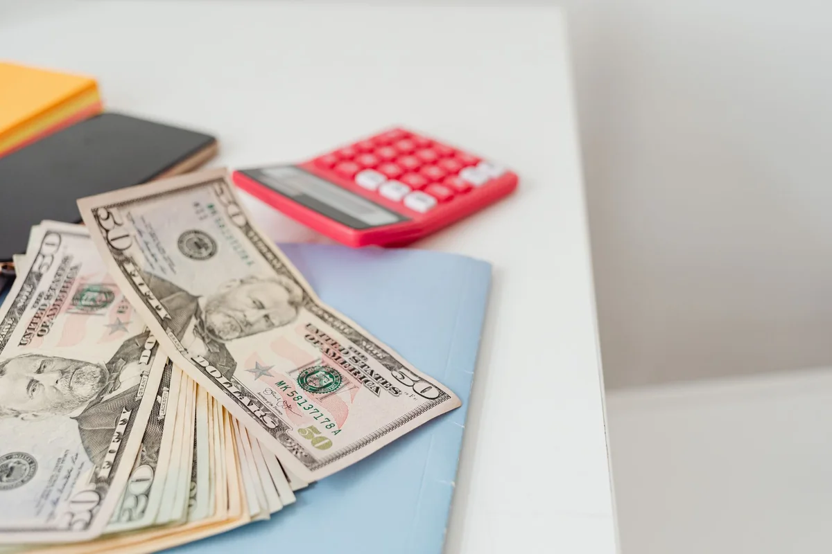 Cash and a calculator on a desk, standing in for the shrinking cash offer of the renegotiation trap when selling a house in Iowa